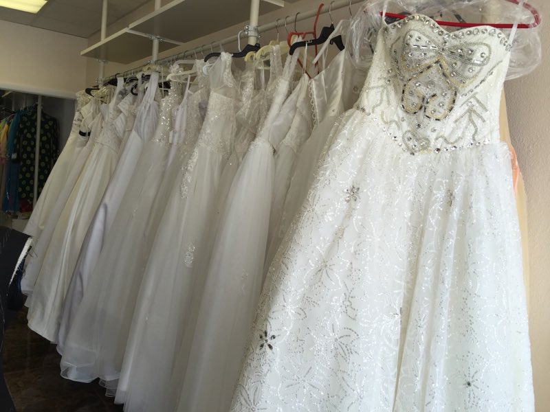 A rack of white bridal and formal gowns waiting for alterations