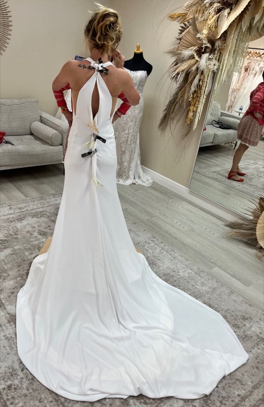A bride from behind in a fitted white gown with a keyhole back at the bridal salon